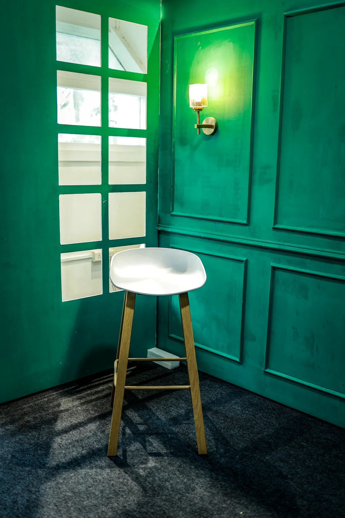 The green panelled doorway, wall light and stool inside Trendtag Studio