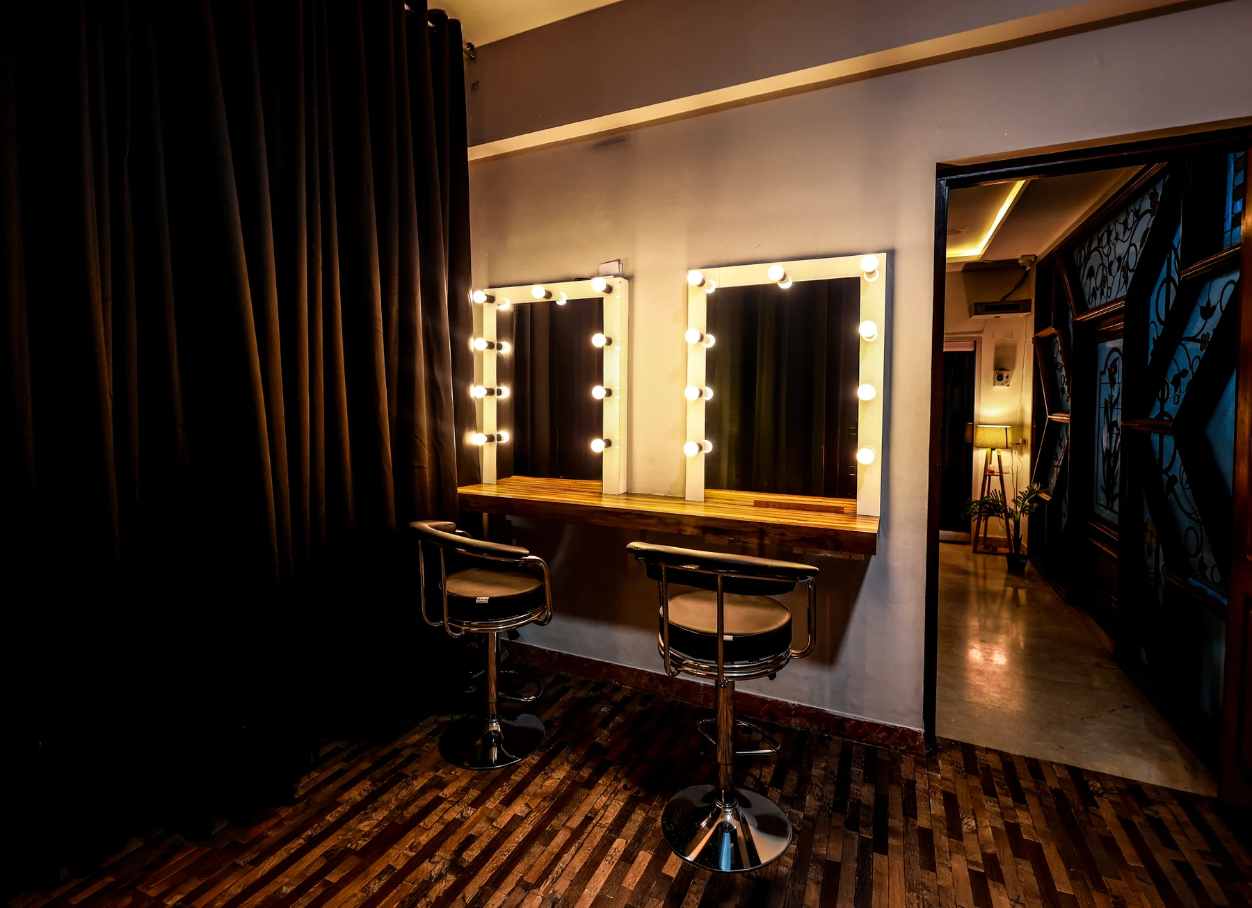 Two illuminated mirrors and styling chairs in the makeup space