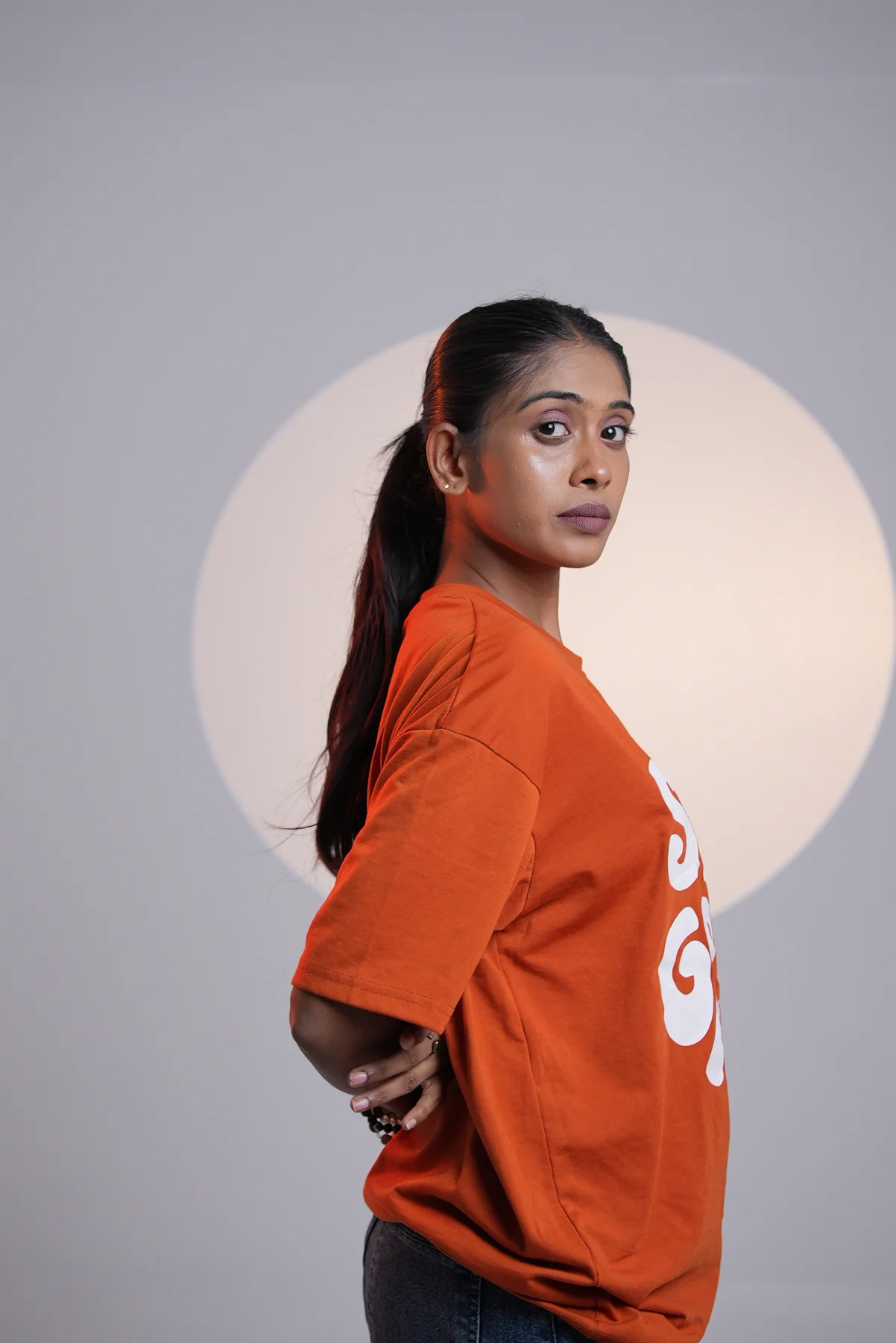 An orange T-shirt against a circular light projection.