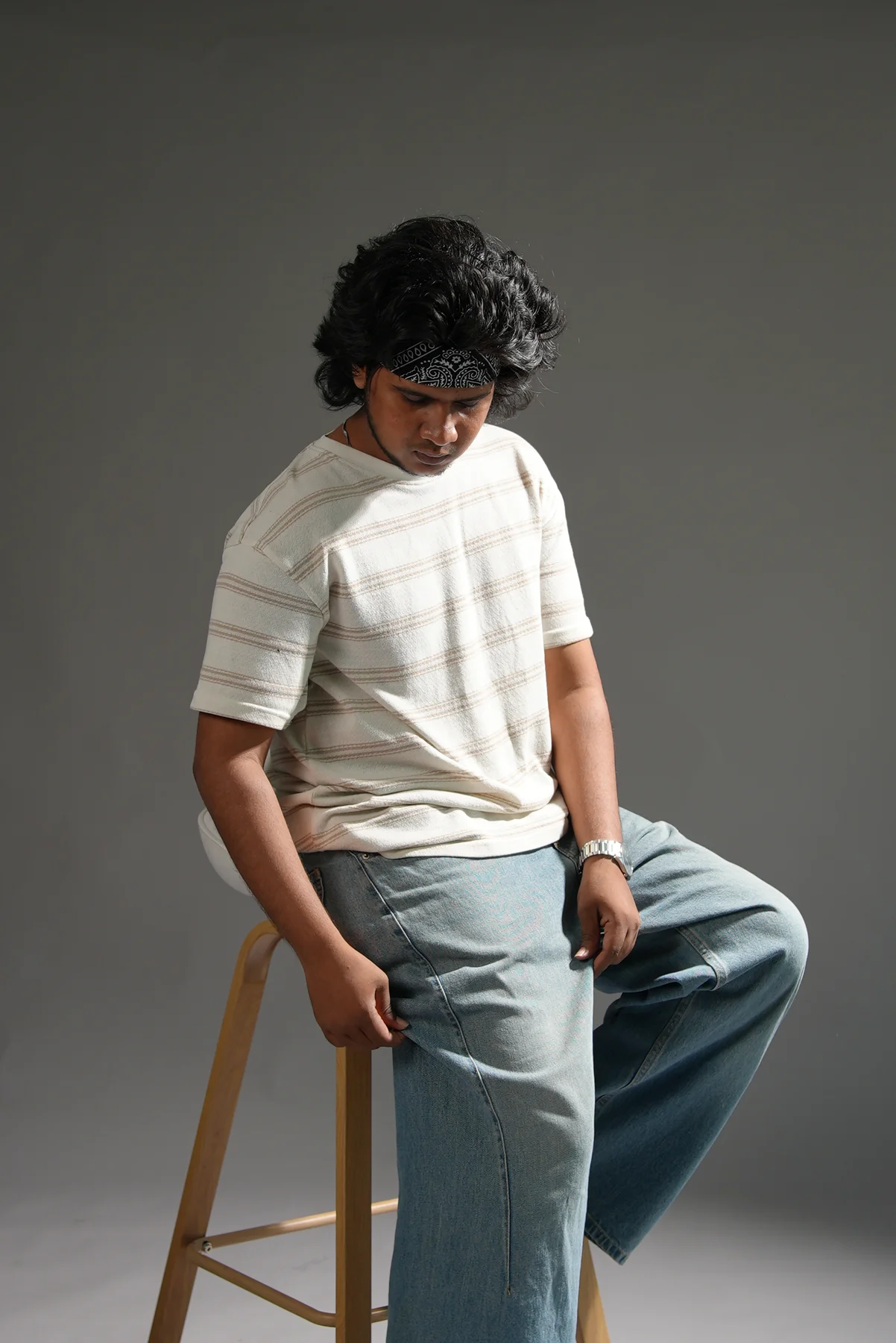 A seated portrait in a neutral studio setting.